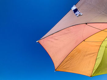 Close-up low angle view of blue sky and beach umbrella part