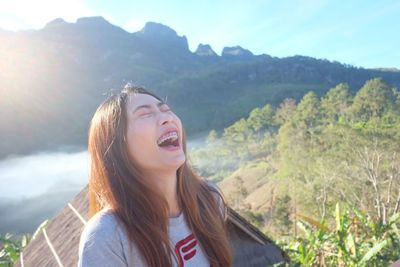 Young woman laughing against mountains