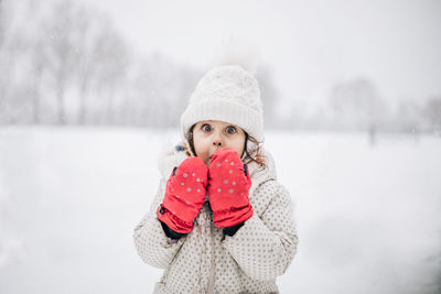 Portrait of young woman standing on snow covered field