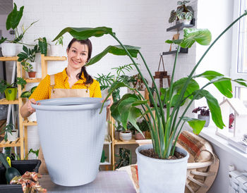 Portrait of young woman holding potted plant