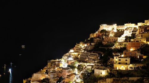 Illuminated buildings in city against clear sky at night