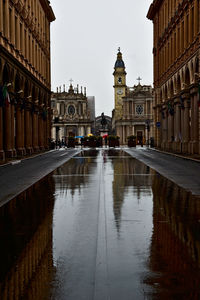 Canal amidst buildings in city during rainy season