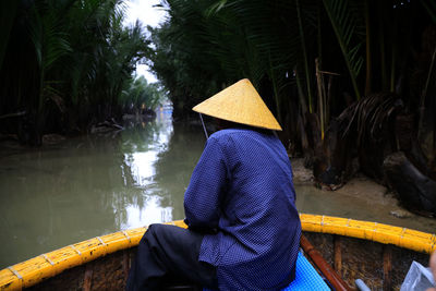 Rear view of woman with umbrella standing against trees