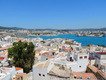 High angle view of townscape by sea against clear blue sky