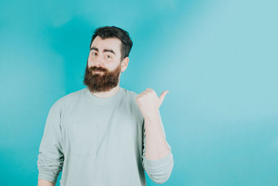 Portrait of young man with arms crossed against blue background