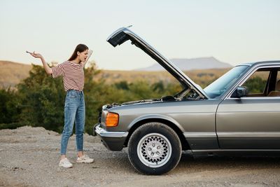 Rear view of woman standing on car