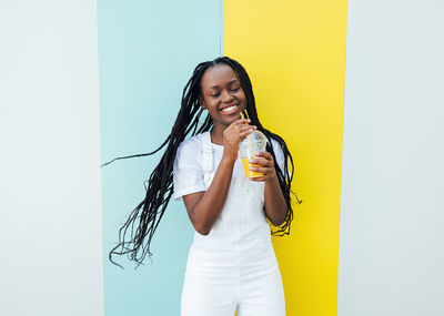 Portrait of young woman drinking water against white background