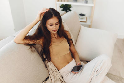 Portrait of young woman sitting on bed at home