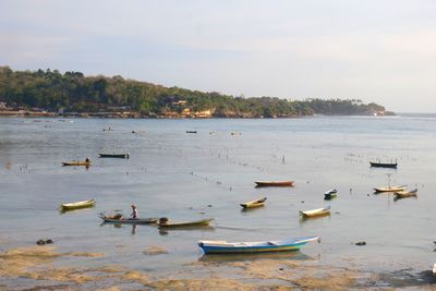 Rowboats in lake against sky