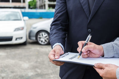 Cropped hands of man signing on insurance paper