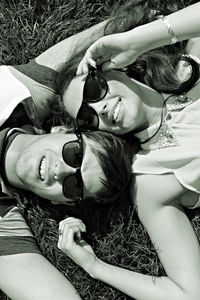 High angle portrait of happy siblings relaxing on grassy field