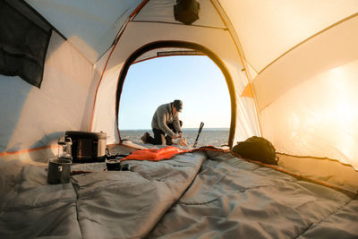 Man camping at beach seen through tent