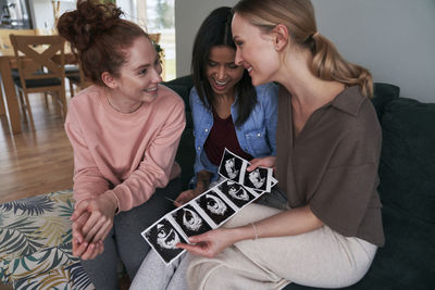 Smiling female friends looking at ultrasound photos
