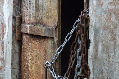 Close-up of rusty metal chain by door