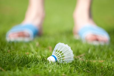 Low section of person standing by shuttlecock on grass