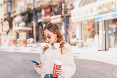 Full length of woman holding mobile phone in city