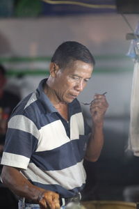 Side view of young a man  standing at street food stall