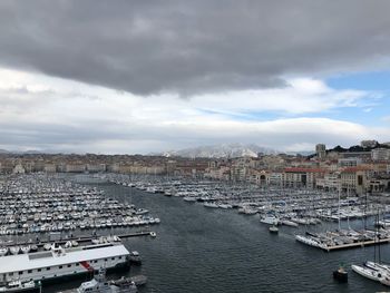 Aerial view of boats moored at harbor against cloudy sky