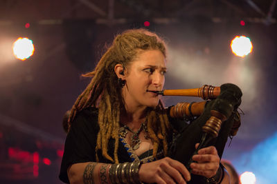 Full length portrait of woman holding illuminated lighting equipment