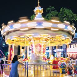 Illuminated carousel in amusement park at night