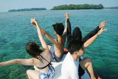 Rear view of people enjoying in sea
