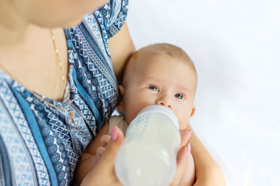 Mother feeding milk to baby girl with bottle