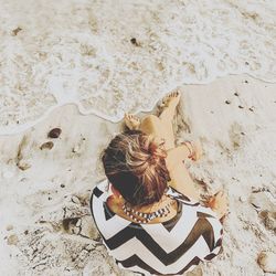 High angle view of woman sitting on sand at beach