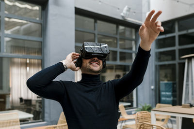 Businessman stretching hand while using virtual reality headset at cafe