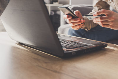 Midsection of man using mobile phone on table