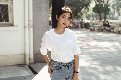 Portrait of smiling young woman standing against built structure