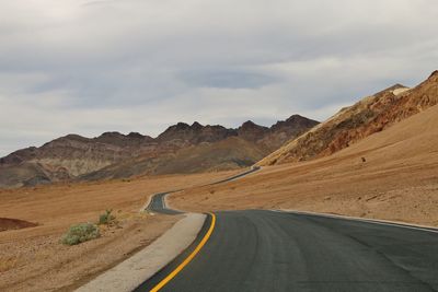 Empty road by mountains against sky