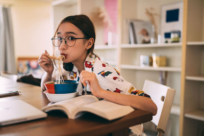 Young woman using mobile phone while sitting at home