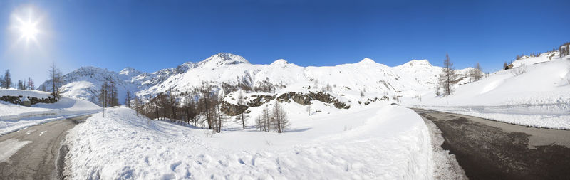 Panoramic view of snow covered mountains against clear blue sky