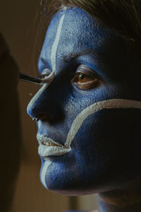 Close-up of woman looking away while applying paint on face