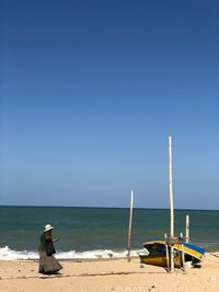 Rear view of man looking at sea against clear sky