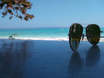 Sunglasses on beach against clear sky