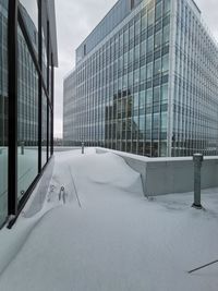 Modern building in snow covered city against sky