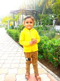 Portrait of smiling girl standing against yellow plants