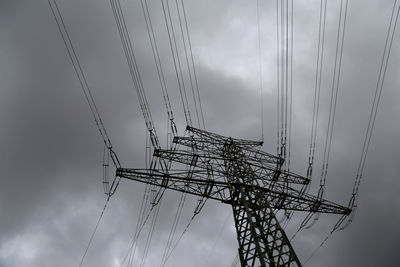 Low angle view of silhouette electricity pylon against sky