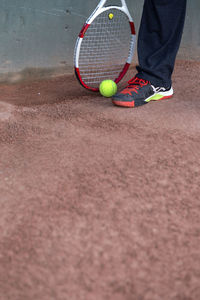 Low section of man with tennis ball and racket