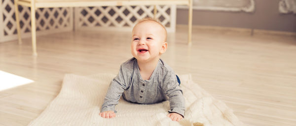 Portrait of cute baby boy on wooden floor