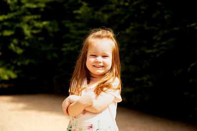 Portrait of smiling young woman standing against trees