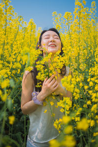 Midsection of woman standing amidst yellow flowering plants