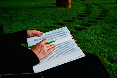 Midsection of woman reading book at park