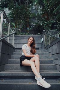 Portrait of smiling woman sitting on staircase outdoors