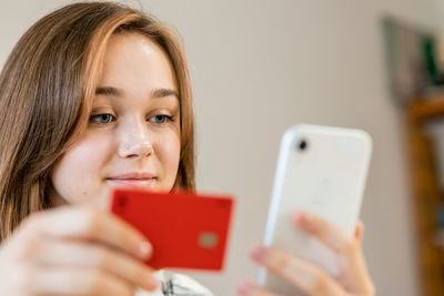 Young woman makes purchases online with a credit card using a smartphone at home. indoors.