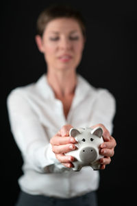 Midsection of doctor holding piggy bank