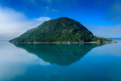 Scenic view of lake by mountains against blue sky