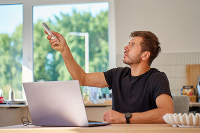 Portrait of young man using laptop while sitting on table