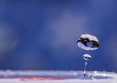 Close-up of water drop falling on blue sea
